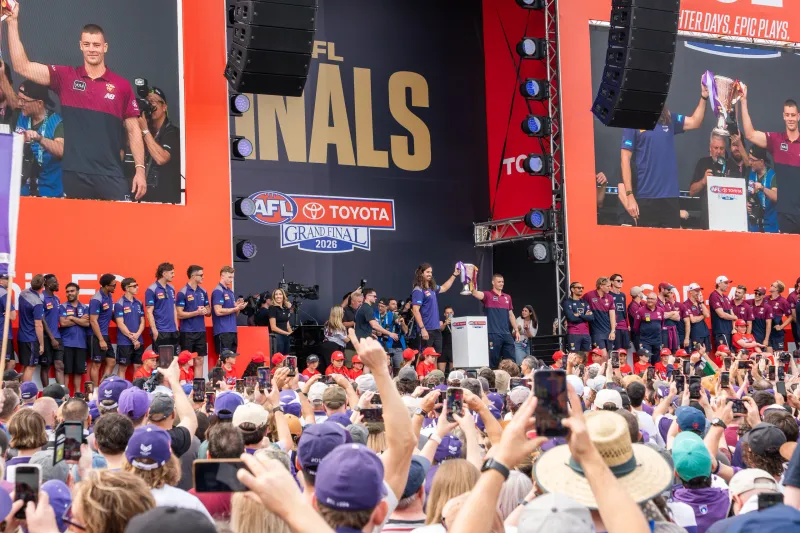 Crowd holding phones aloft as the premiership cup is raised on the AFL Grand Final parade stage in Melbourne